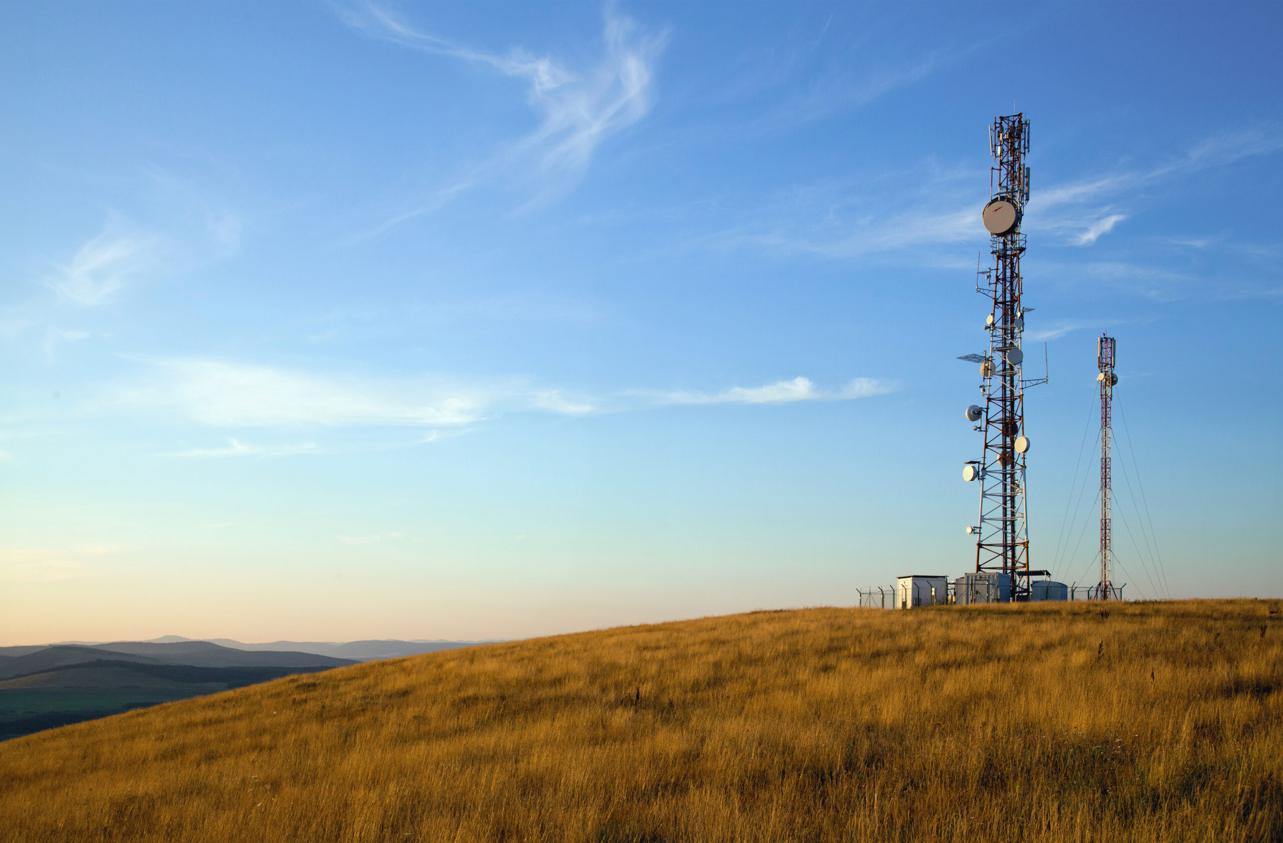 communication towers on top of hill with blue sky background
